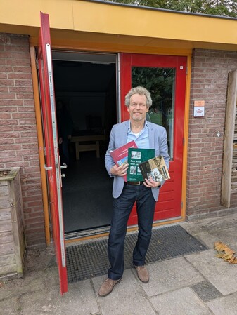 Thomas van Duin, laat, na de lezing, de boeken over onze wijk zien